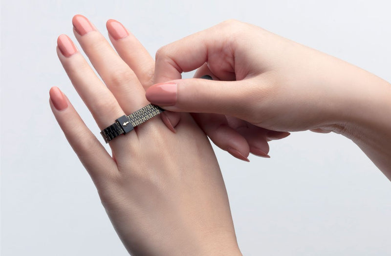 Using a ring sizer to measure around the base of your ring finger for an accurate fit