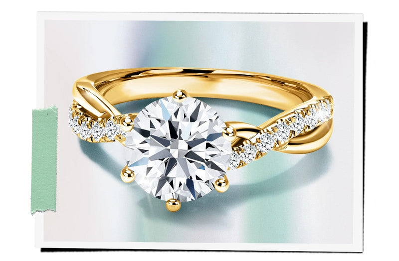 Yellow gold diamond engagement ring with twisted band and six-prong setting, featuring a round brilliant cut center stone and pavé side diamonds.