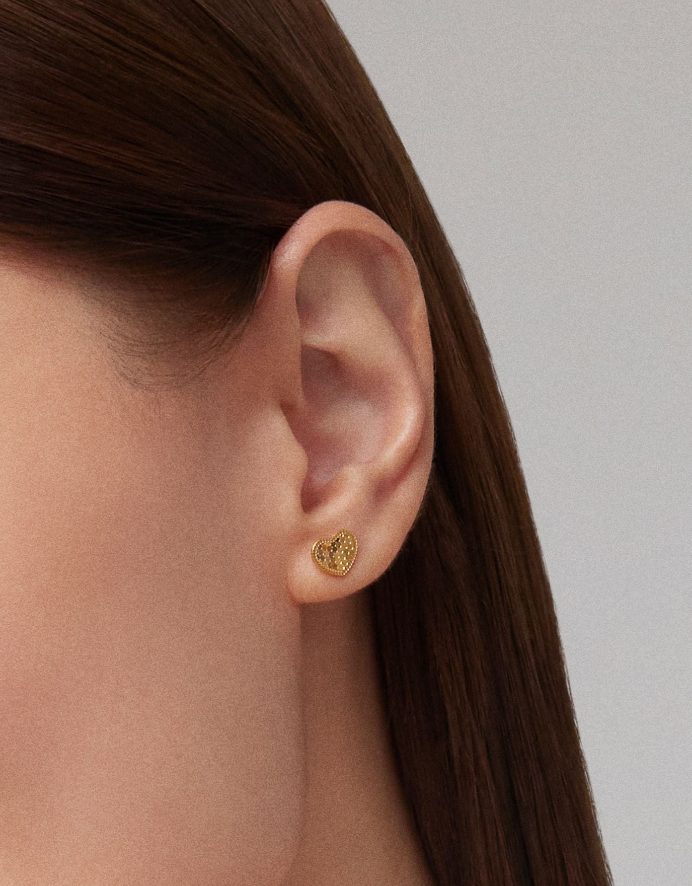 woman wearing LVC stud earrings in 999 pure gold with heart shaped design