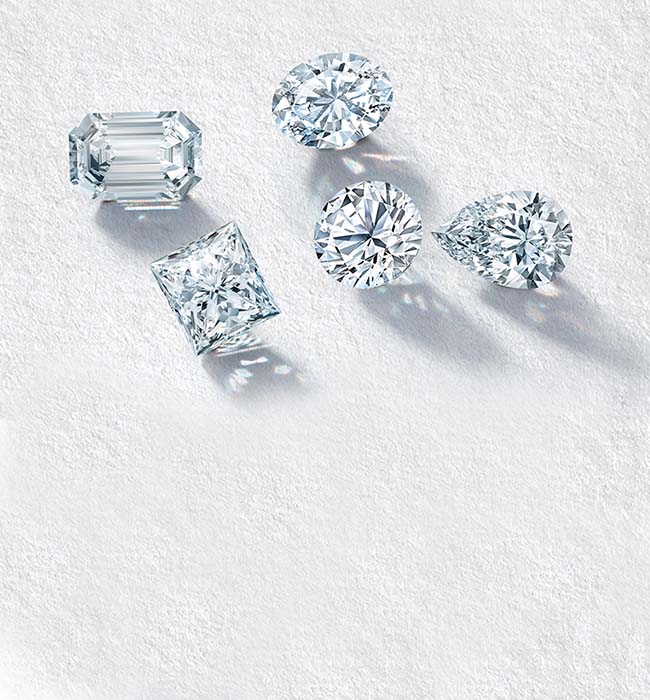 A collection of five diamond cuts showcasing emerald, oval, princess, round brilliant, and pear-shaped gemstones