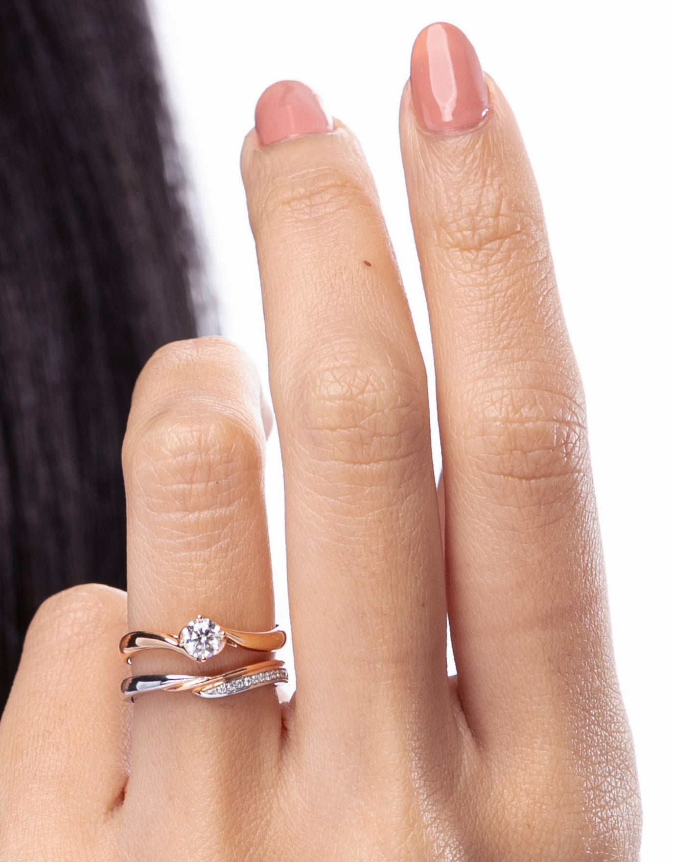 LVC wedding band designed with a curved row of diamonds in white and rose gold worn on ring finger stacked with another ring