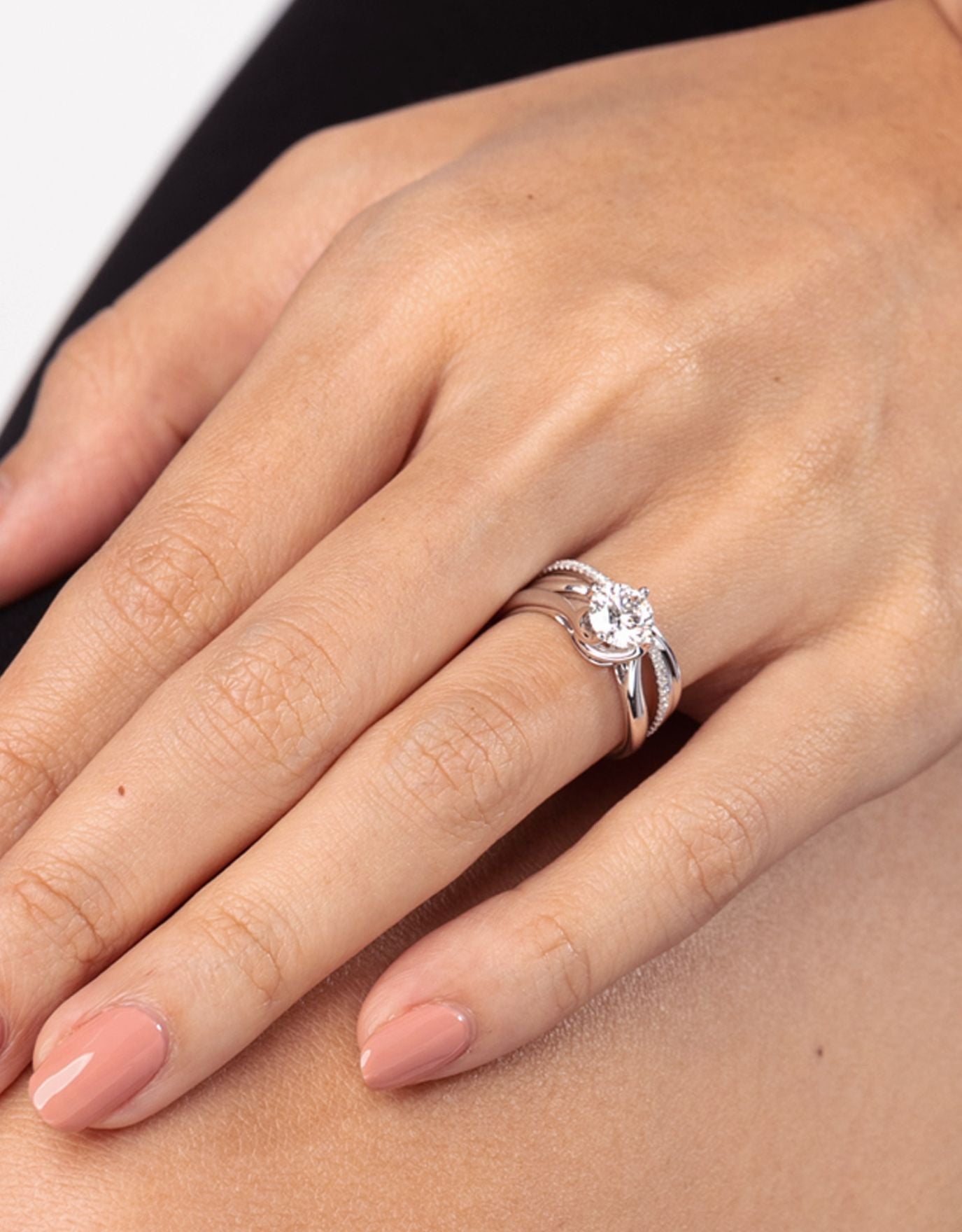 LVC a woman wearing the precieux twisted solitaire diamond ring in white gold on her ring finger stacked with another ring