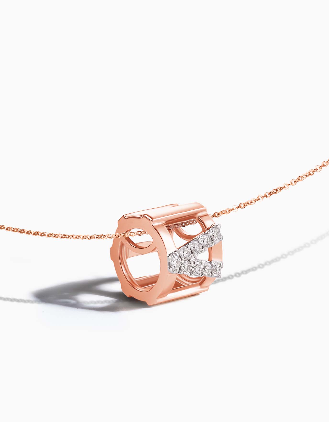close up of the LVC rose gold necklace's pendant in the shape of a barrel with diamonds lined into a v shape