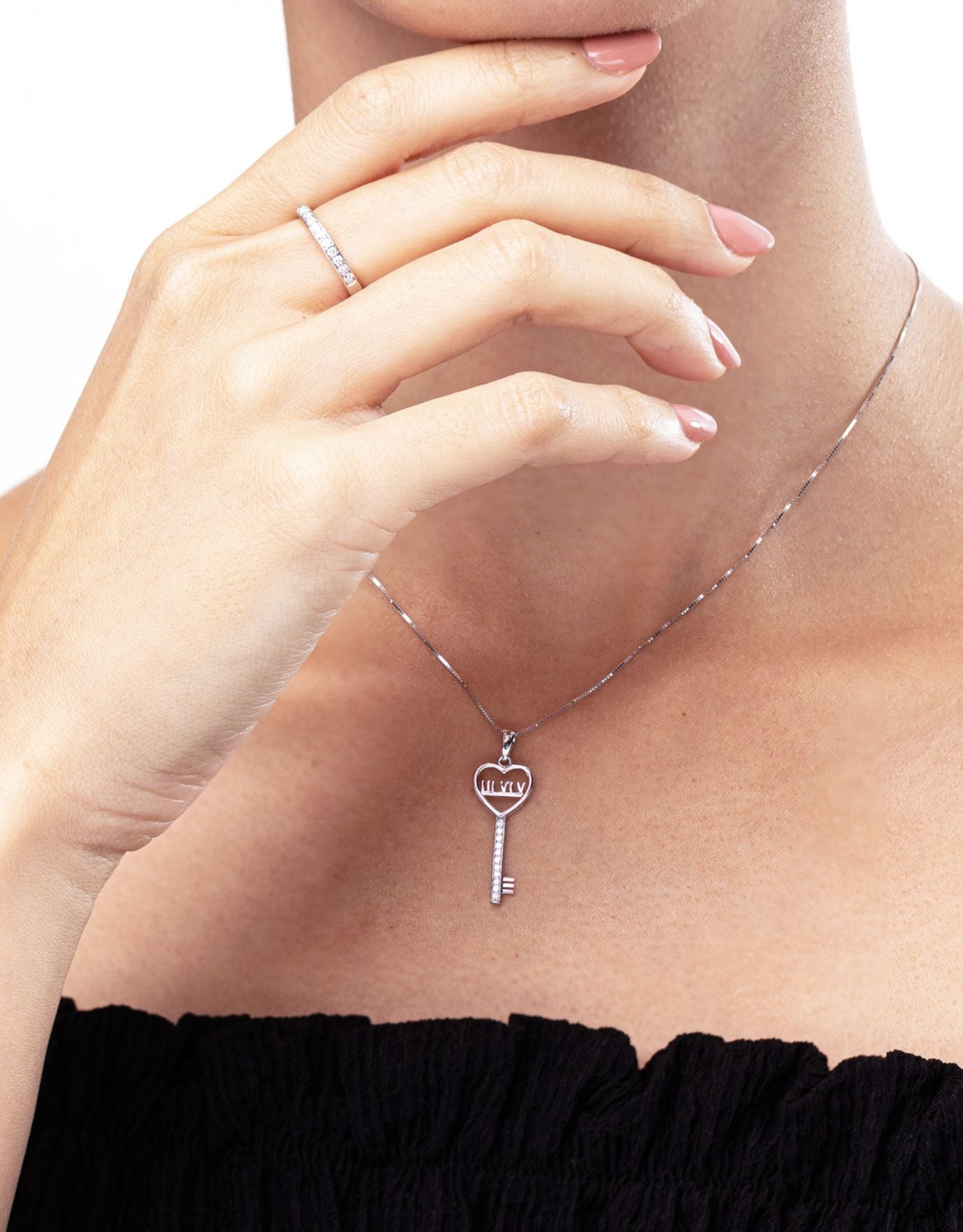 woman wearing LVC necklace in white gold with a key pendant designed with roman numerals encrusted with a line of round diamonds