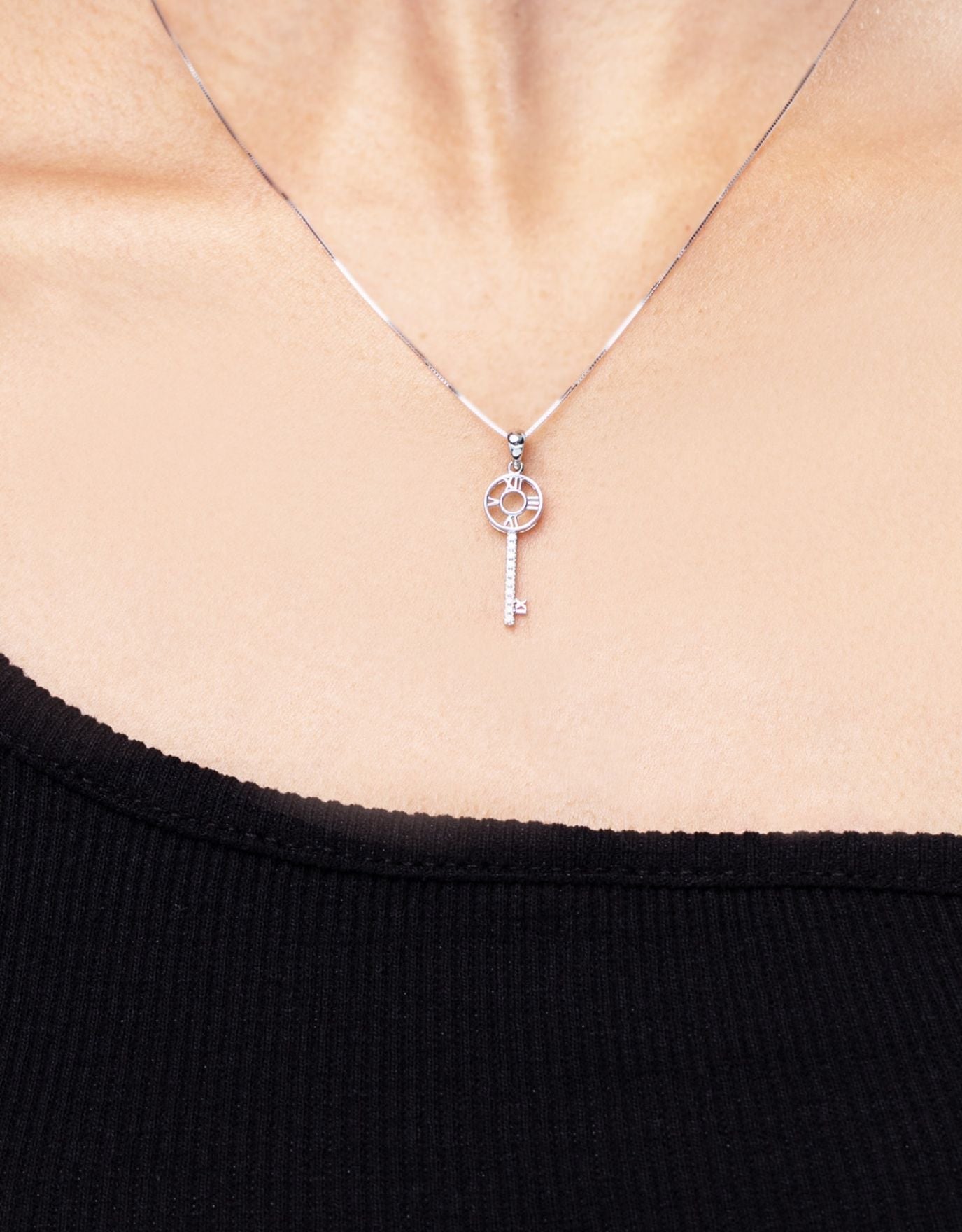 woman wearing LVC necklace in white gold designed with roman numerals arranged in the shape of the clock encrusted with a row of round diamonds
