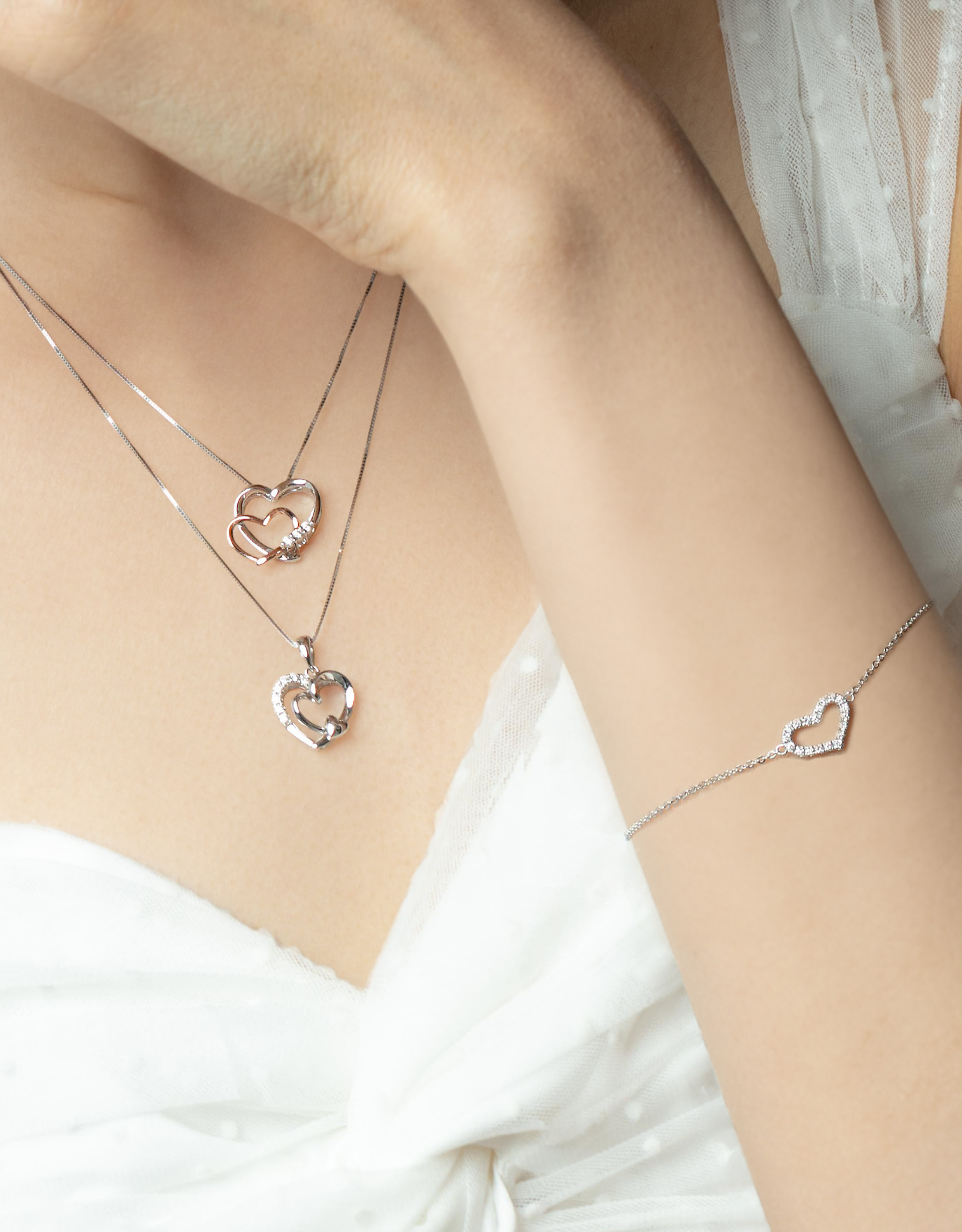 woman wearing LVC diamond necklace designed with 2 interlocking hearts in white and rose gold