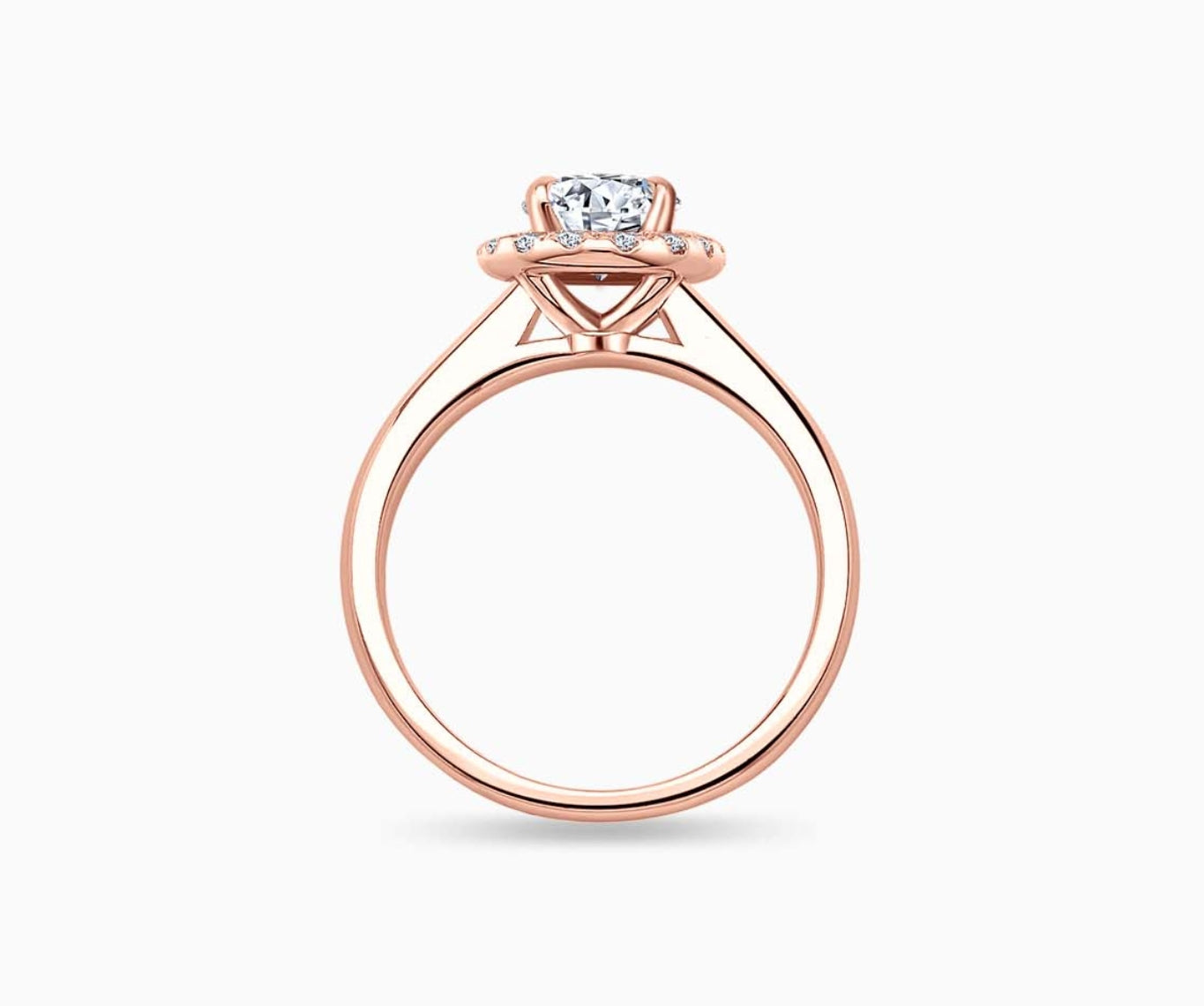 side view of an oval-cut diamond halo engagement ring set on rose gold with a tapered plain band design