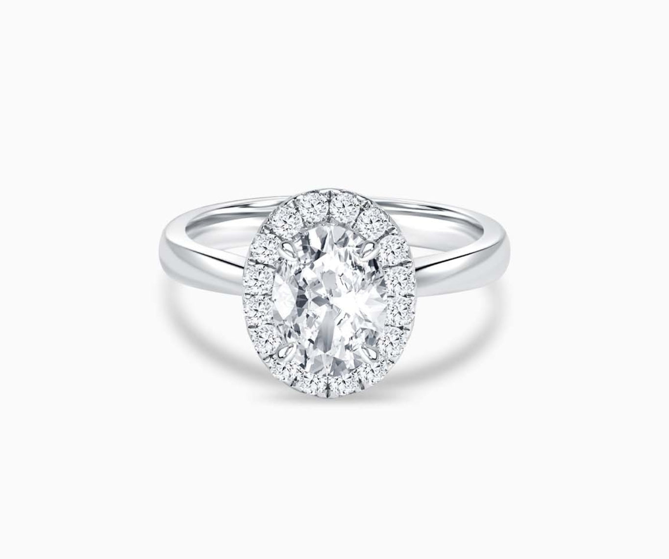 oval cut diamond halo engagement ring with a tapered plain white gold band 