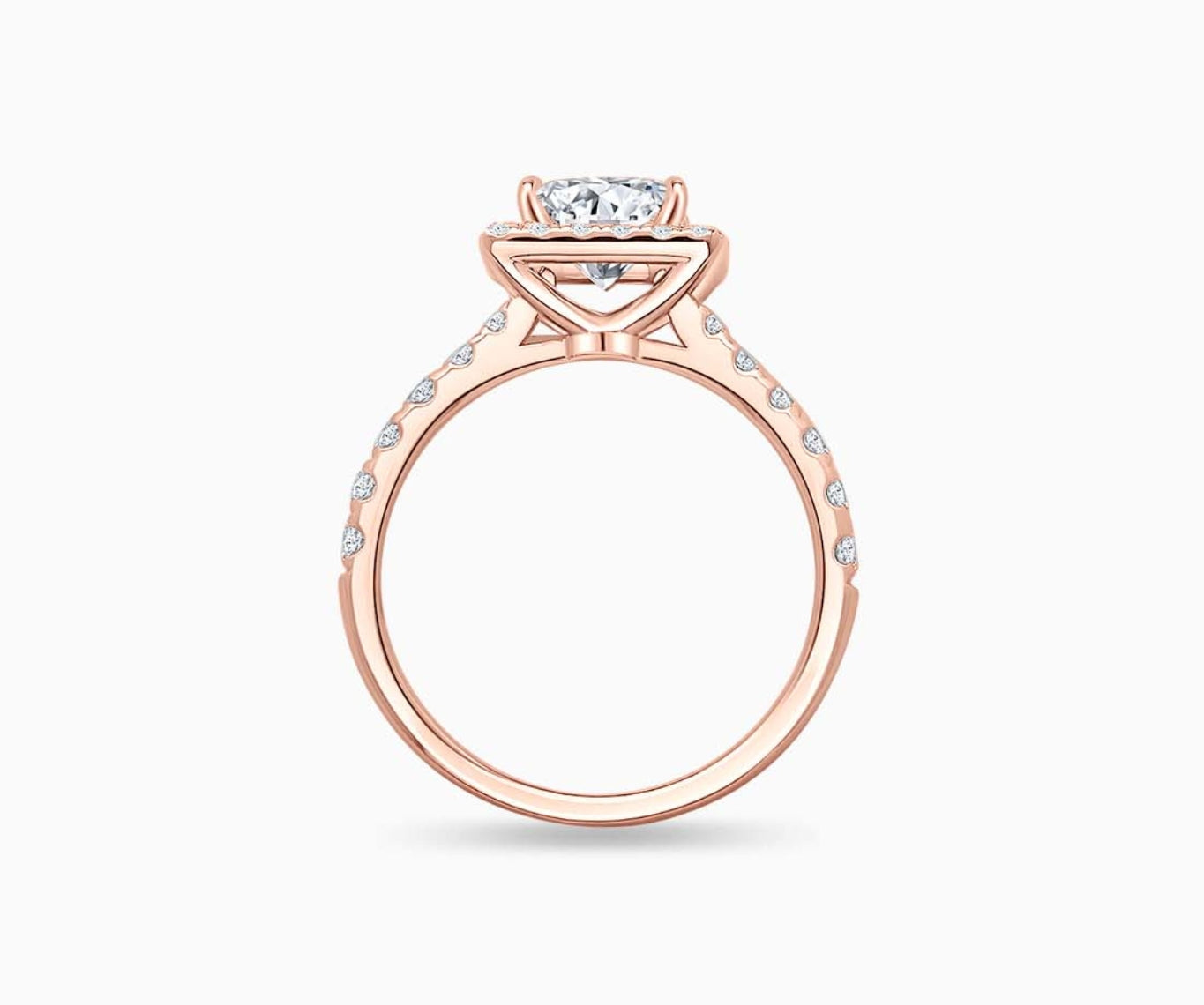 side view of emerald cut diamond halo engagement ring set in rose gold with tapered pave band design