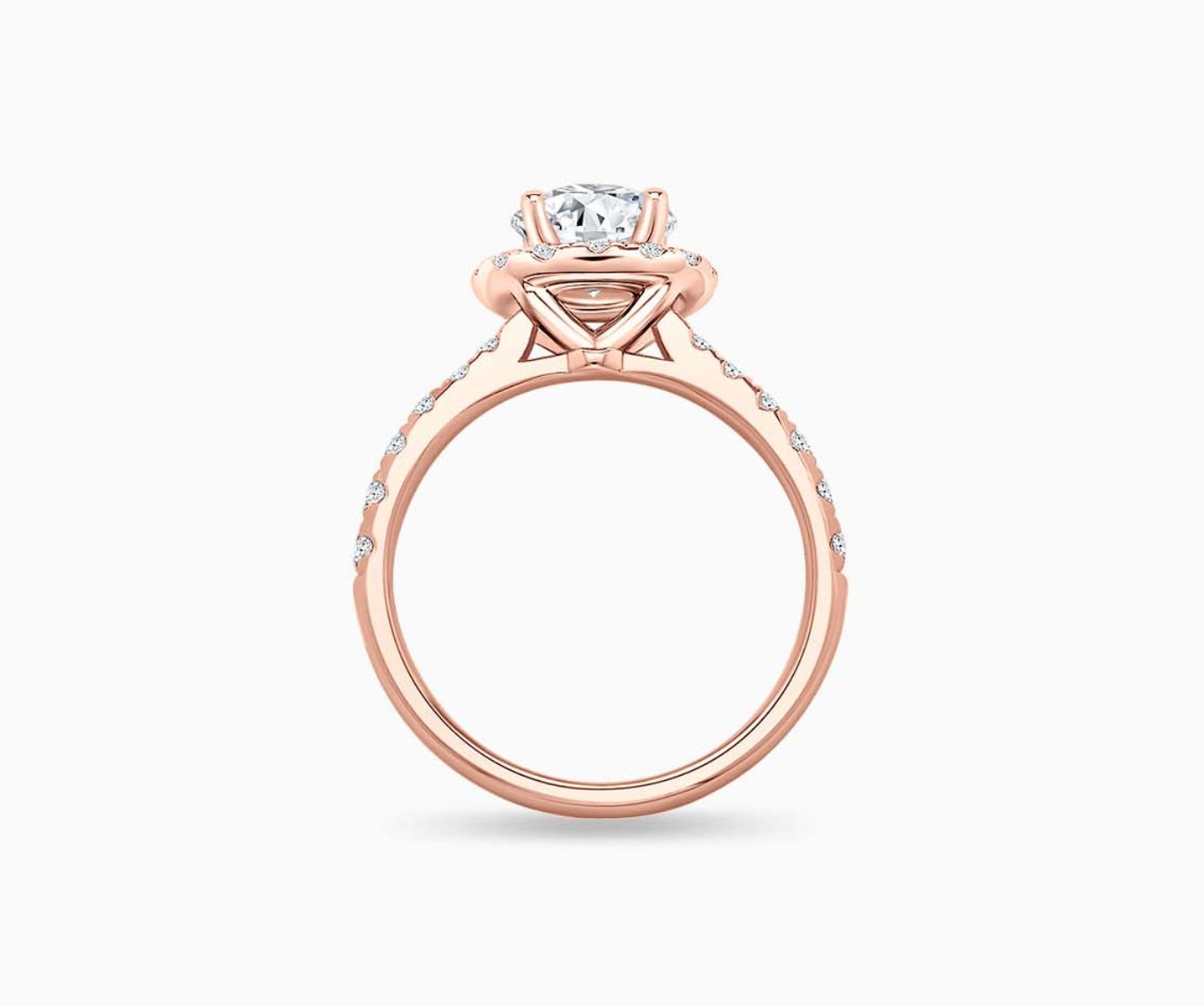 side view of round diamond halo engagement ring set in rose gold with a tapered pave band design