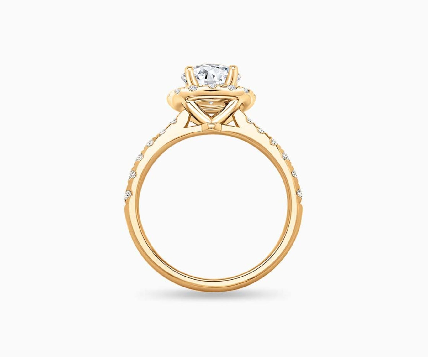 side view of Round cut diamond halo engagement ring set on yellow gold with a tapered pave band design