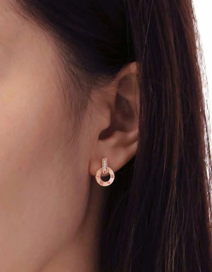 Rose gold earring worn by a person with dark hair.